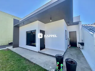 Fachada externa de uma casa moderna com paredes brancas e garagem escura.
