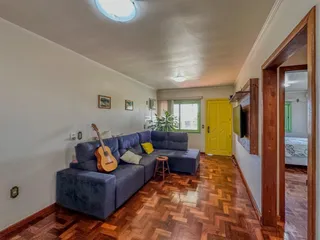 Sala de estar com sofá azul e piso de madeira no interior da residência.