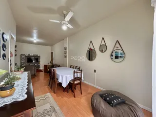 Ambiente interno de uma sala de jantar com piso de madeira e móveis.