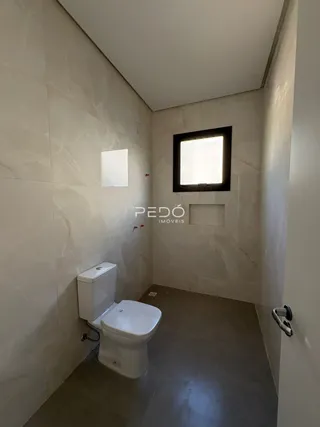 Foto do interior de um banheiro com paredes claras e piso de cerâmica.