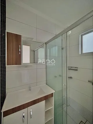 Interior de um banheiro com box de vidro e bancada de madeira.
