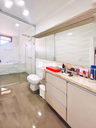 Foto interna de um banheiro com bancada e revestimento de piso claro.