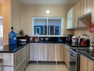 Foto interna da cozinha com armários de madeira clara e bancadas escuras.