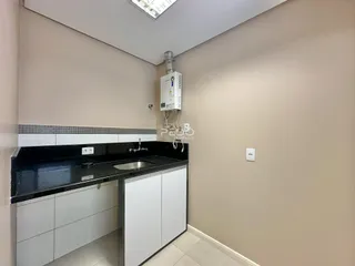 Foto de uma cozinha com armários brancos e bancada escura.