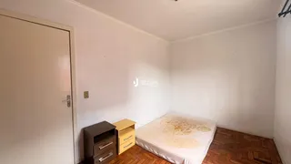 Quarto com cama e piso de madeira em uma residência.