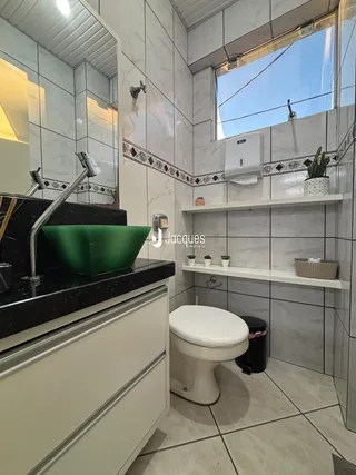 Foto interna de um banheiro com revestimento de azulejos brancos e cinzas.