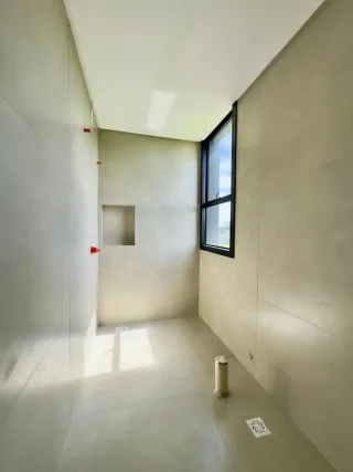 Hall de um imóvel com paredes brancas e uma janela.