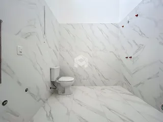 Um banheiro com revestimento de mármore branco nas paredes e piso.