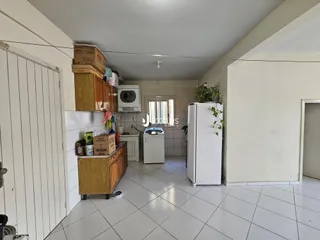 Interior de uma cozinha ou área comum com armários de madeira e piso de cerâmica.