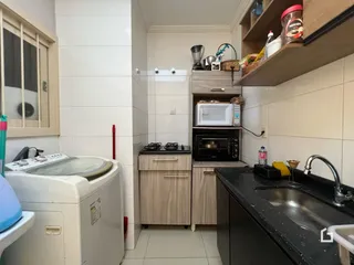 Imagem de uma cozinha com armários de madeira e revestimento branco.