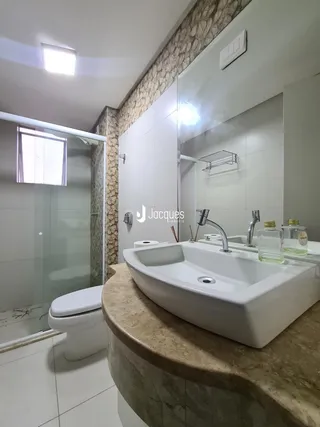 Banheiro com bancada de mármore e box de vidro.