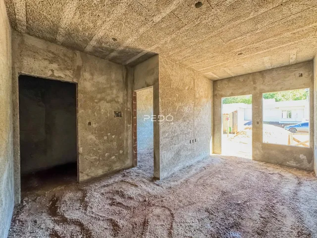 Interior de um espaço com paredes de concreto aparente e portas abertas.