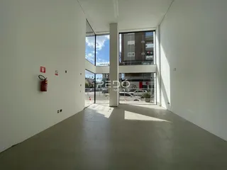 Hall de entrada com paredes brancas e piso de concreto.