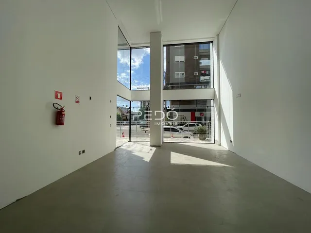 Hall de entrada com paredes brancas e piso de concreto.