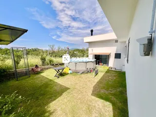 Vista de um jardim gramado com vegetação ao fundo.