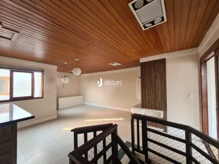 Sala de estar com teto de madeira e piso claro.