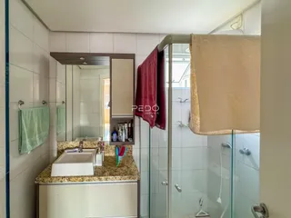 Banheiro com box de vidro e bancada de granito.