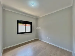 Ambiente interno de uma sala com piso de madeira clara e parede cinza.