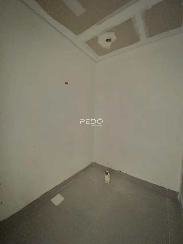 Vista interna de um cômodo com paredes brancas e teto em construção.