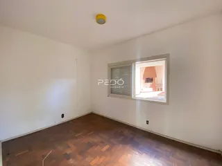 Ambiente interno de uma sala com piso de madeira e janela.