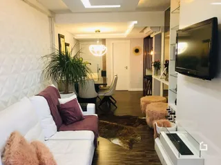 Sala de estar com sofá branco e piso de madeira.
