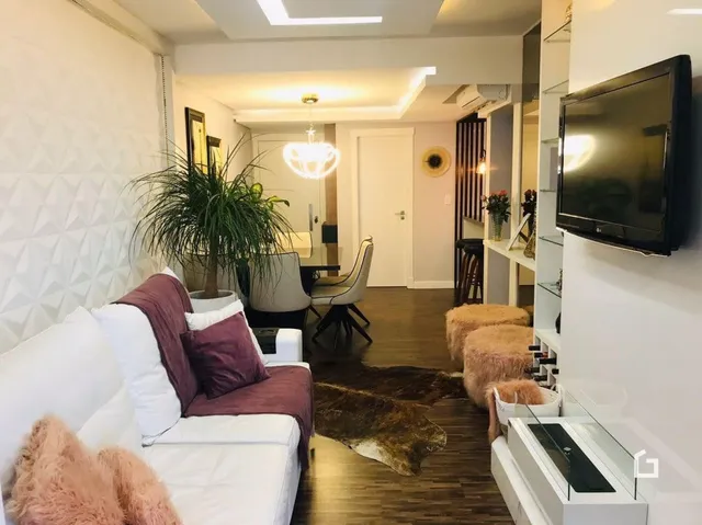Sala de estar com sofá branco e piso de madeira.