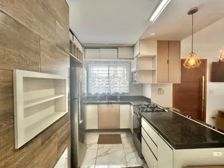 Foto de uma cozinha moderna com armários brancos e bancada escura.