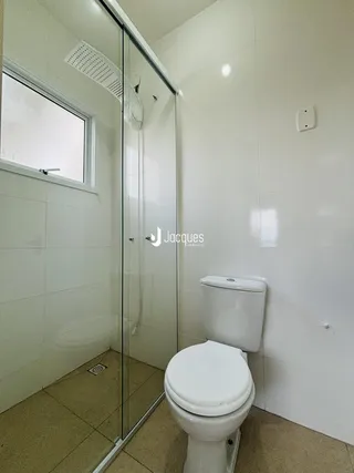 Banheiro com box de vidro e vaso sanitário em cerâmica.
