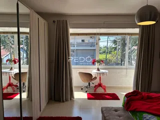 Sala de estar com grandes janelas e cortinas claras.