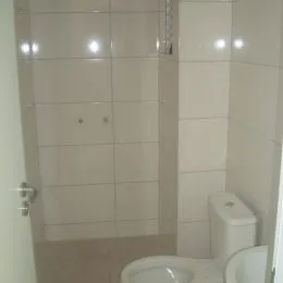 Foto interna de um banheiro com revestimento de azulejos brancos.