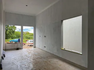 Ambiente interno com paredes brancas e piso de cerâmica em uma área de construção.
