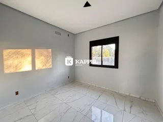 Sala ampla com piso de mármore claro e janela.