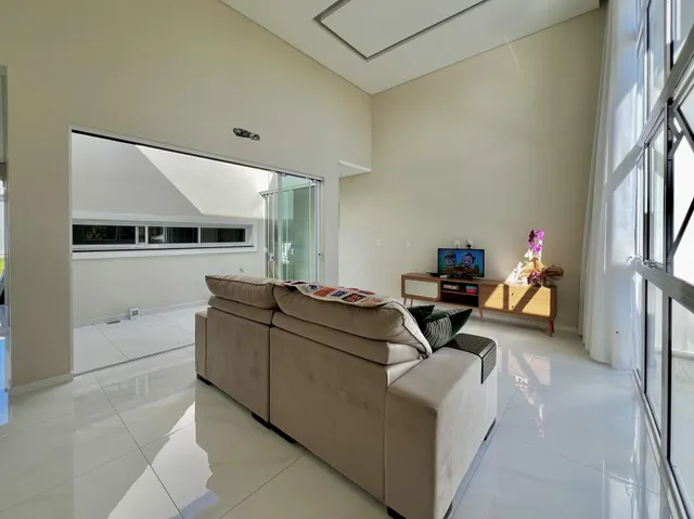 Sala de estar ampla com sofá grande e televisão em ambiente claro.