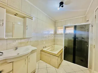 Banheiro com box de vidro e banheira em ambiente claro.