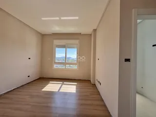 Uma sala com paredes brancas e piso de madeira clara.
