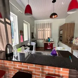 Vista de uma cozinha com bancada escura e revestimento de tijolos aparentes.