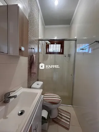 Banheiro com pia branca e box de vidro.