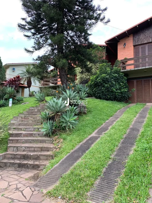 Vista externa de uma propriedade com jardim e escadaria de pedra.