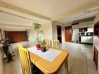 Vista interna de uma sala de jantar com piso de cerâmica e móveis de madeira.