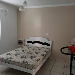 Quarto com cama de casal e paredes claras.