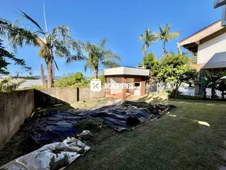 Área externa com gramado e vegetação ao lado de uma construção.