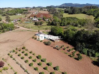 Vista aérea de uma área de campo aberto com vegetação e colinas ao fundo.