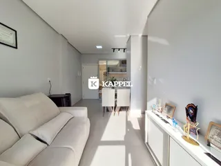 Sala de estar com sofá branco e piso claro, mostrando a área de convivência da residência.