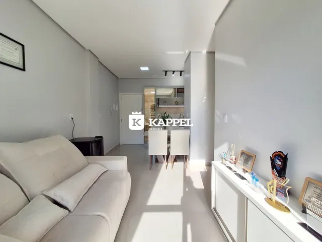 Sala de estar com sofá branco e piso claro, mostrando a área de convivência da residência.