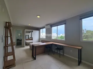 Interior de uma sala com janela grande e móveis de madeira.