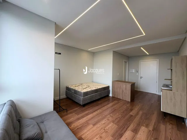 Quarto com piso de madeira e iluminação moderna.