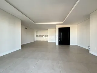 Corredor amplo com paredes brancas e piso claro em uma residência.