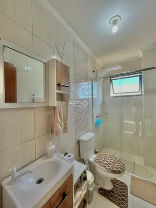 Foto interna de um banheiro com revestimento cerâmico e box de vidro.