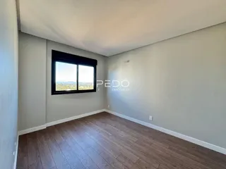 Sala de estar com piso de madeira e vista para a paisagem.