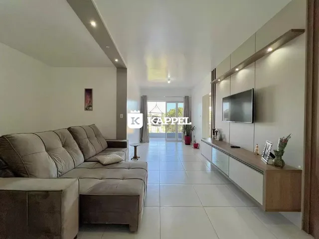 Uma sala de estar ampla e iluminada com sofá e televisão.